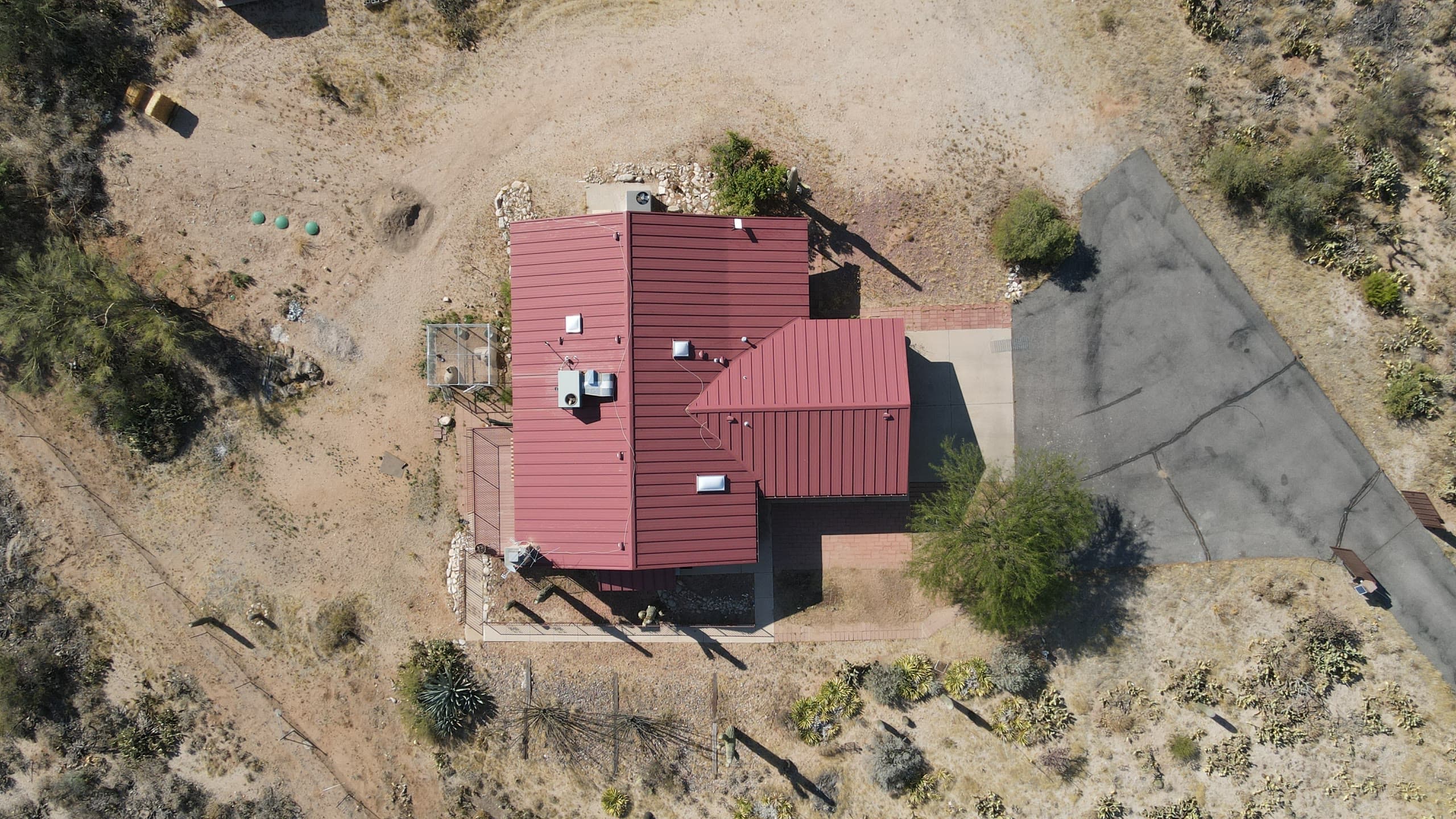 Overhead view of a red metal-roof home on a desert lot