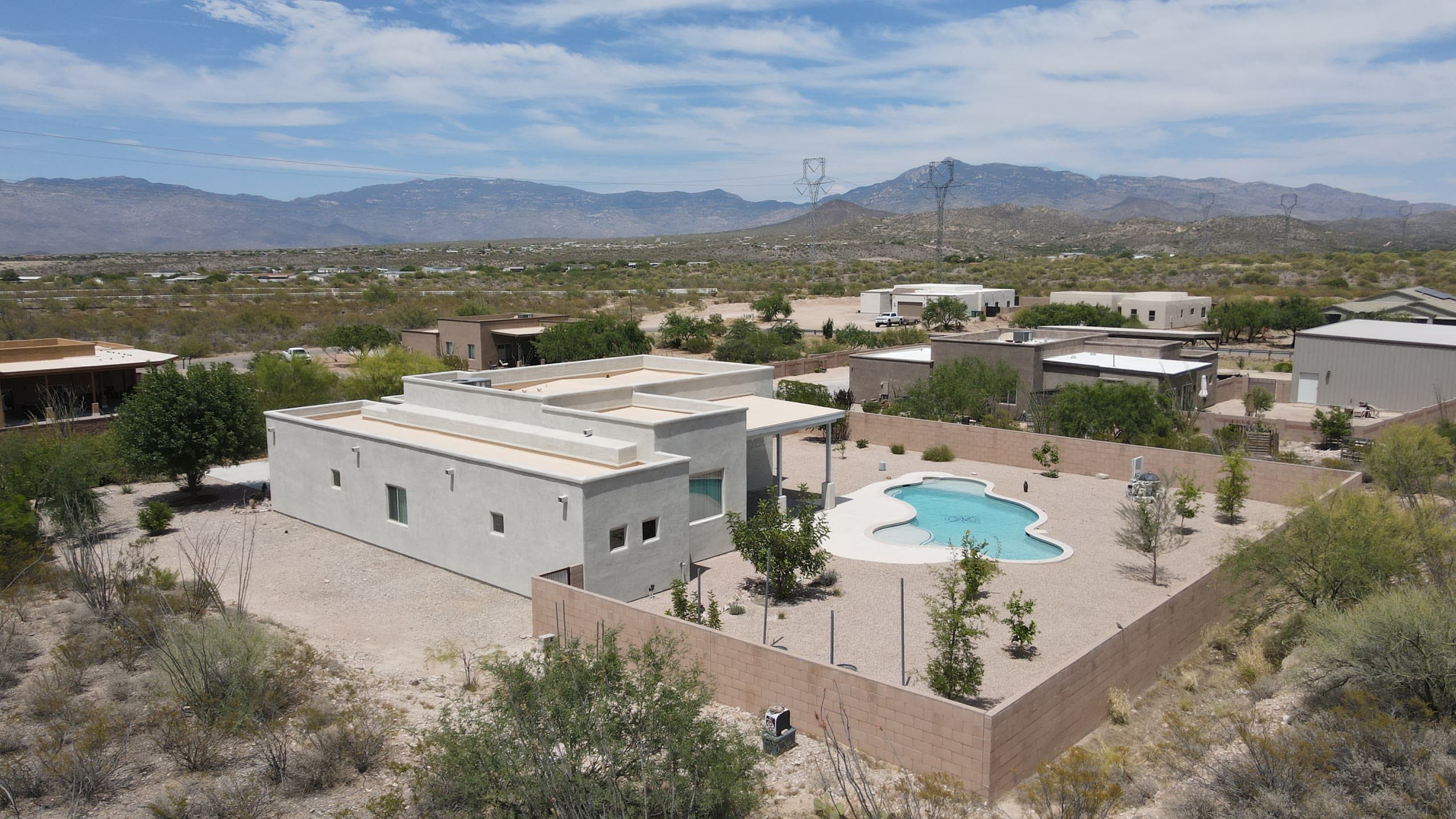 Modern stucco home with a walled pool yard and mountains on the horizon
