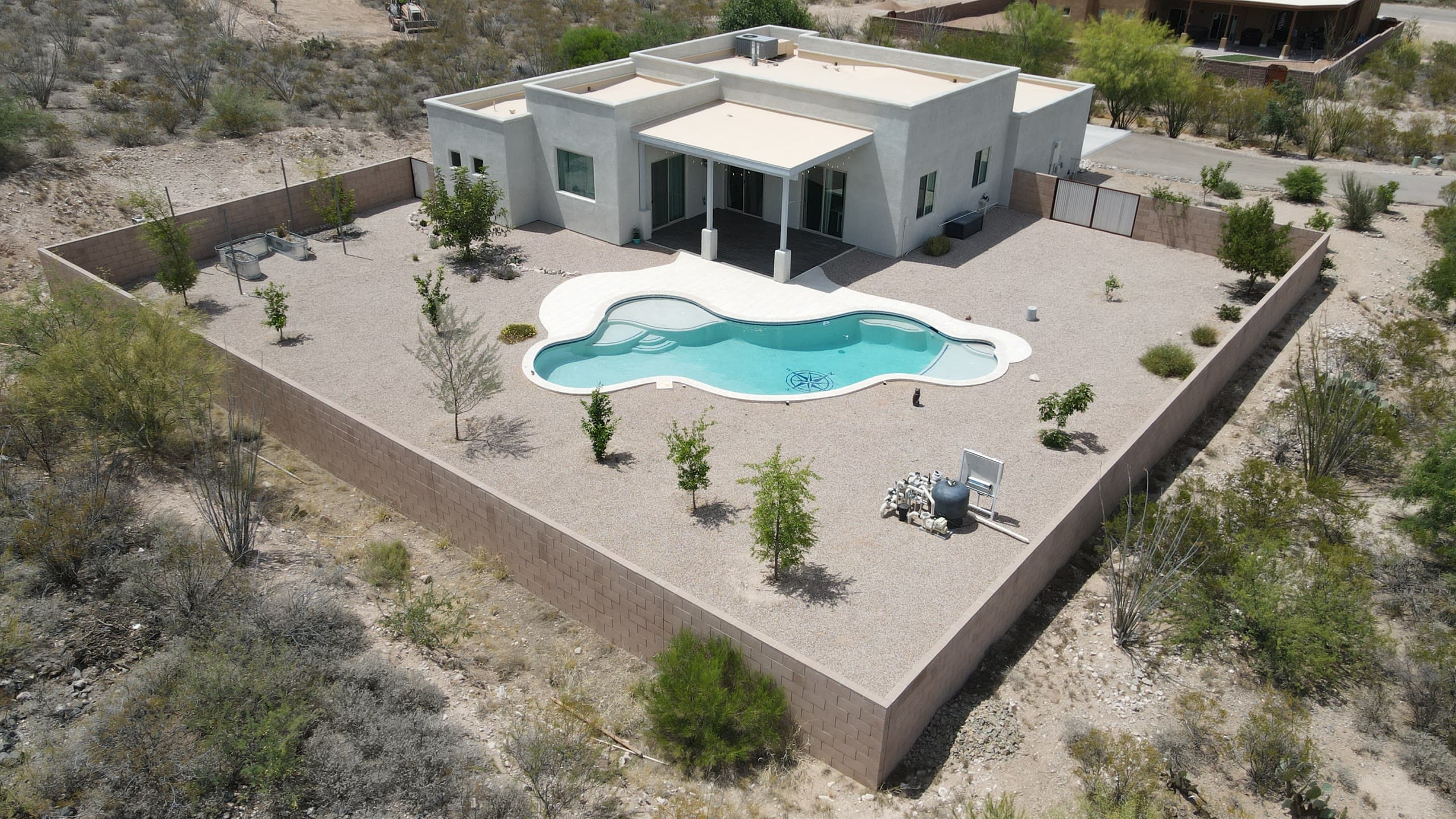 Modern flat-roof home with a freeform turquoise pool inside a walled desert yard