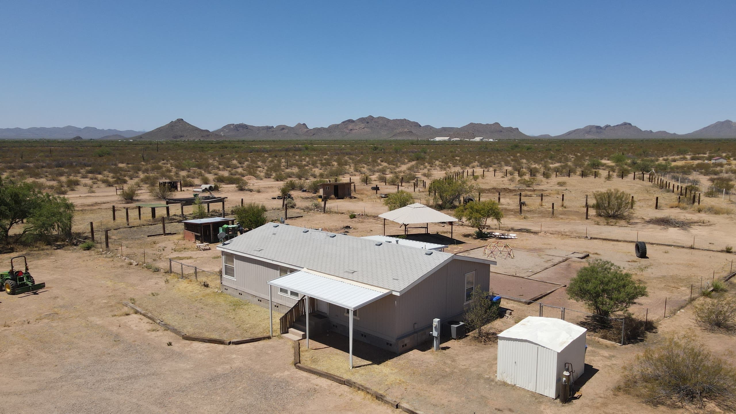 Manufactured home with corrals and a shade ramada on desert acreage