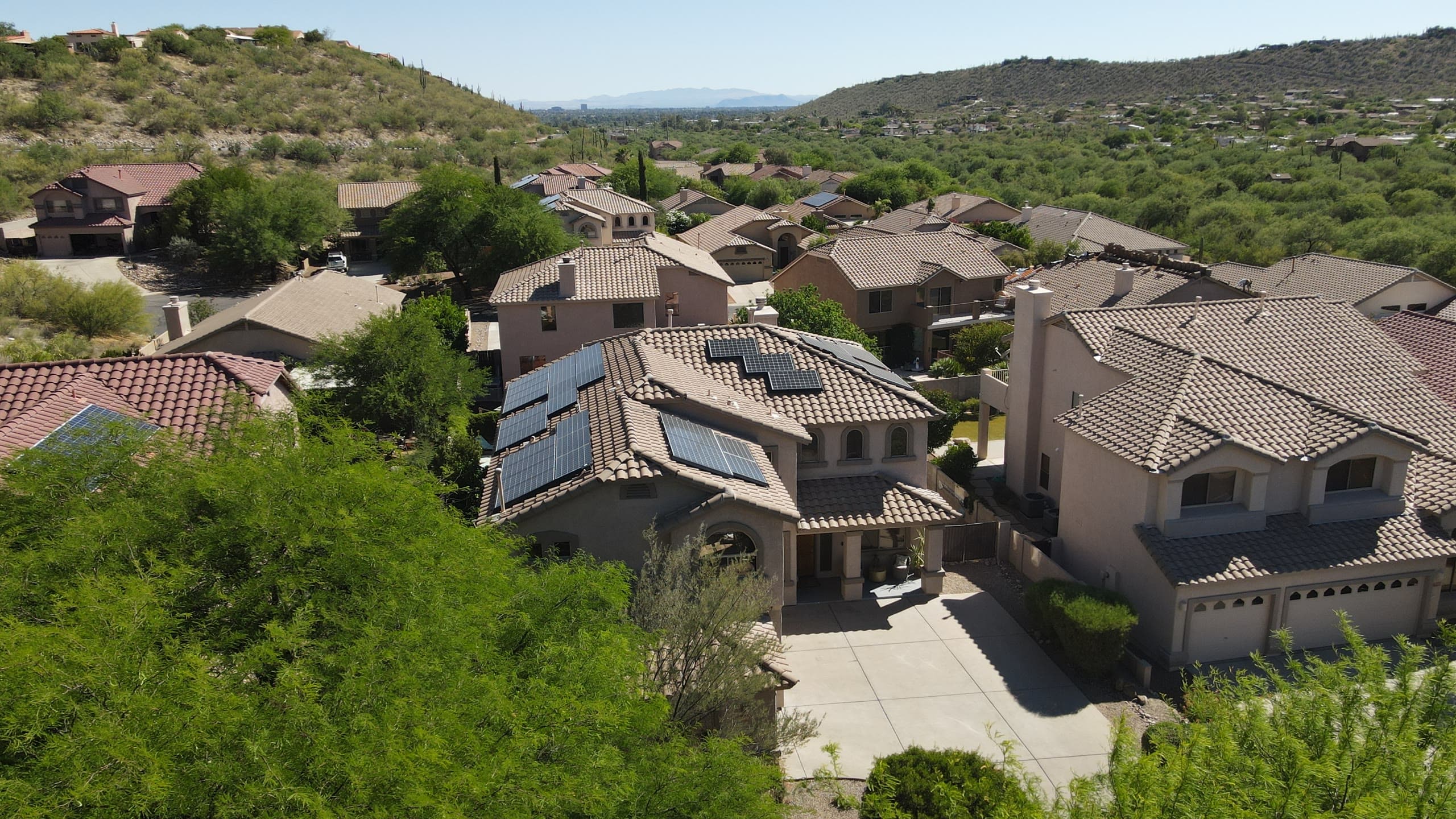 Two-story tile-roof homes with rooftop solar on a wooded hillside