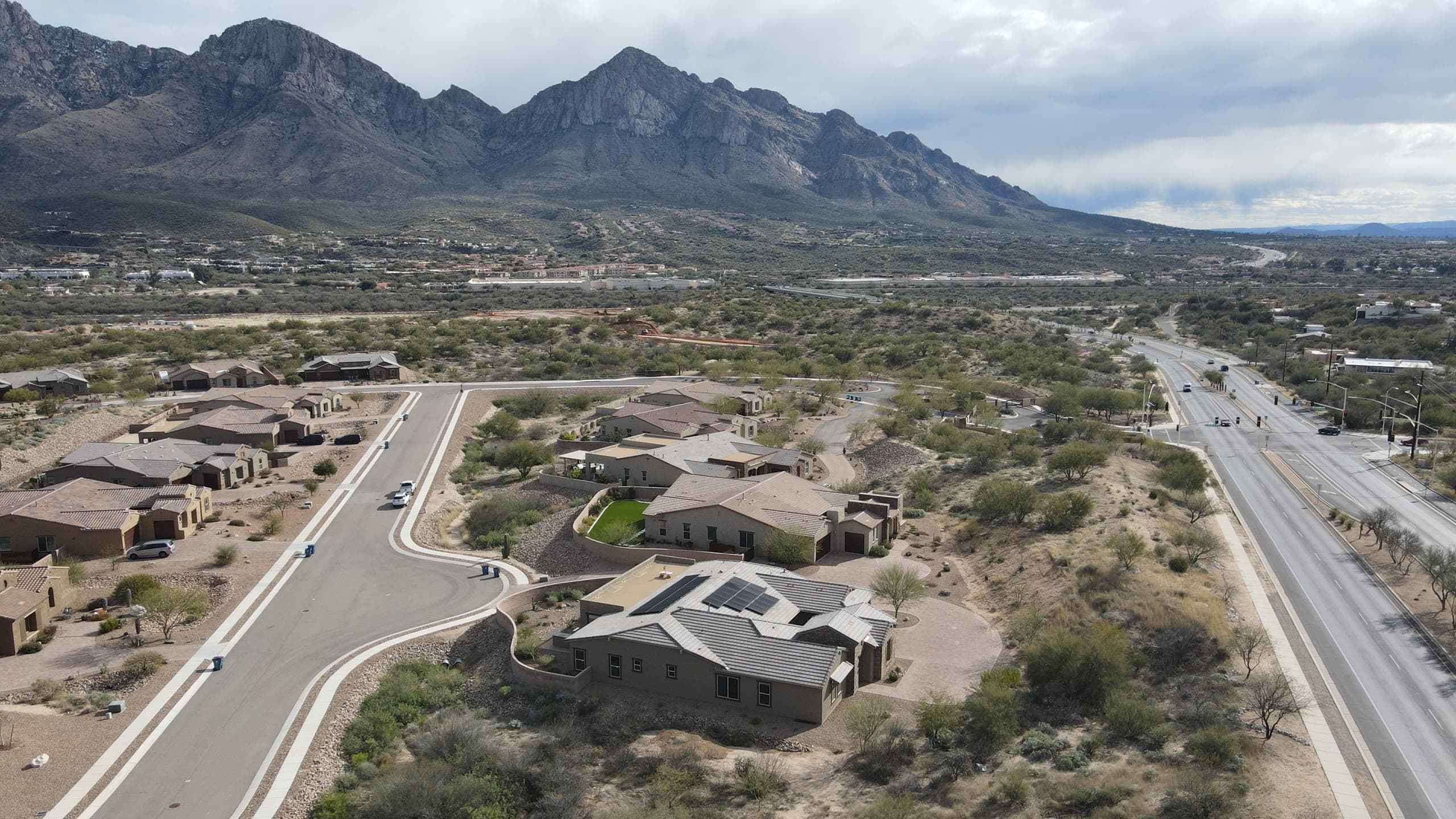 New homes along a curving street with Pusch Ridge behind