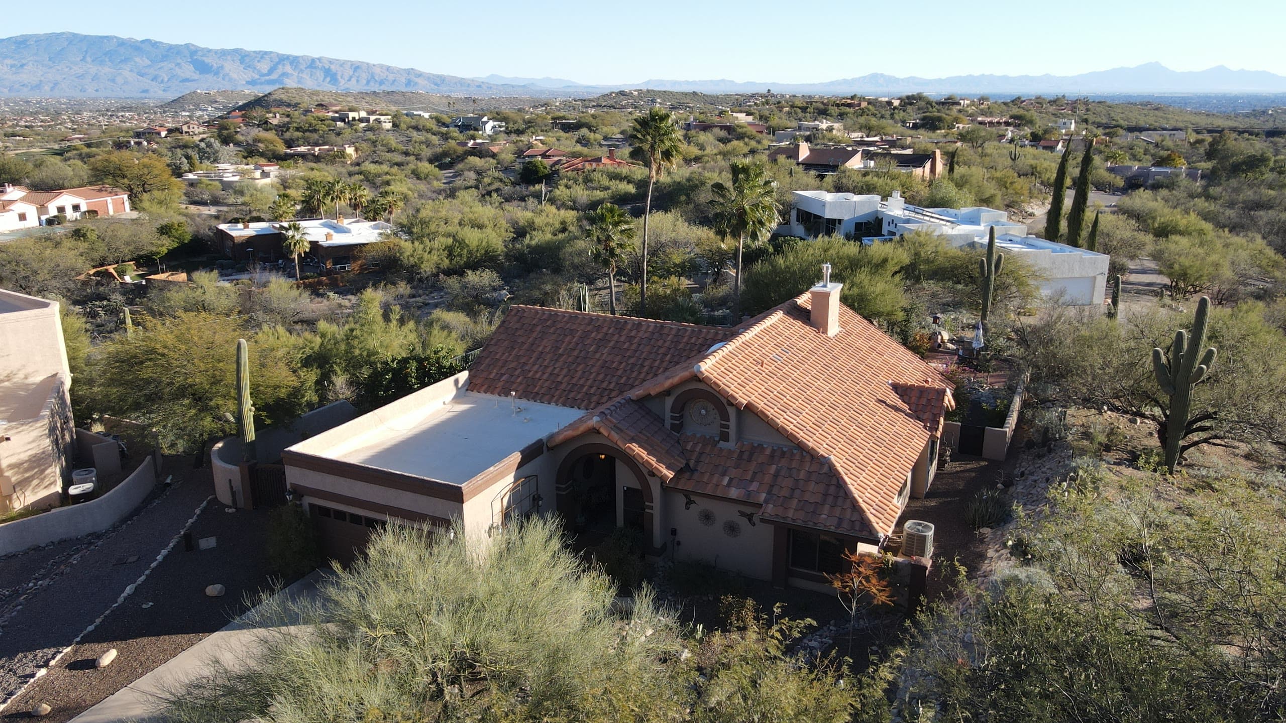 Tile-roof home among saguaros with city views beyond