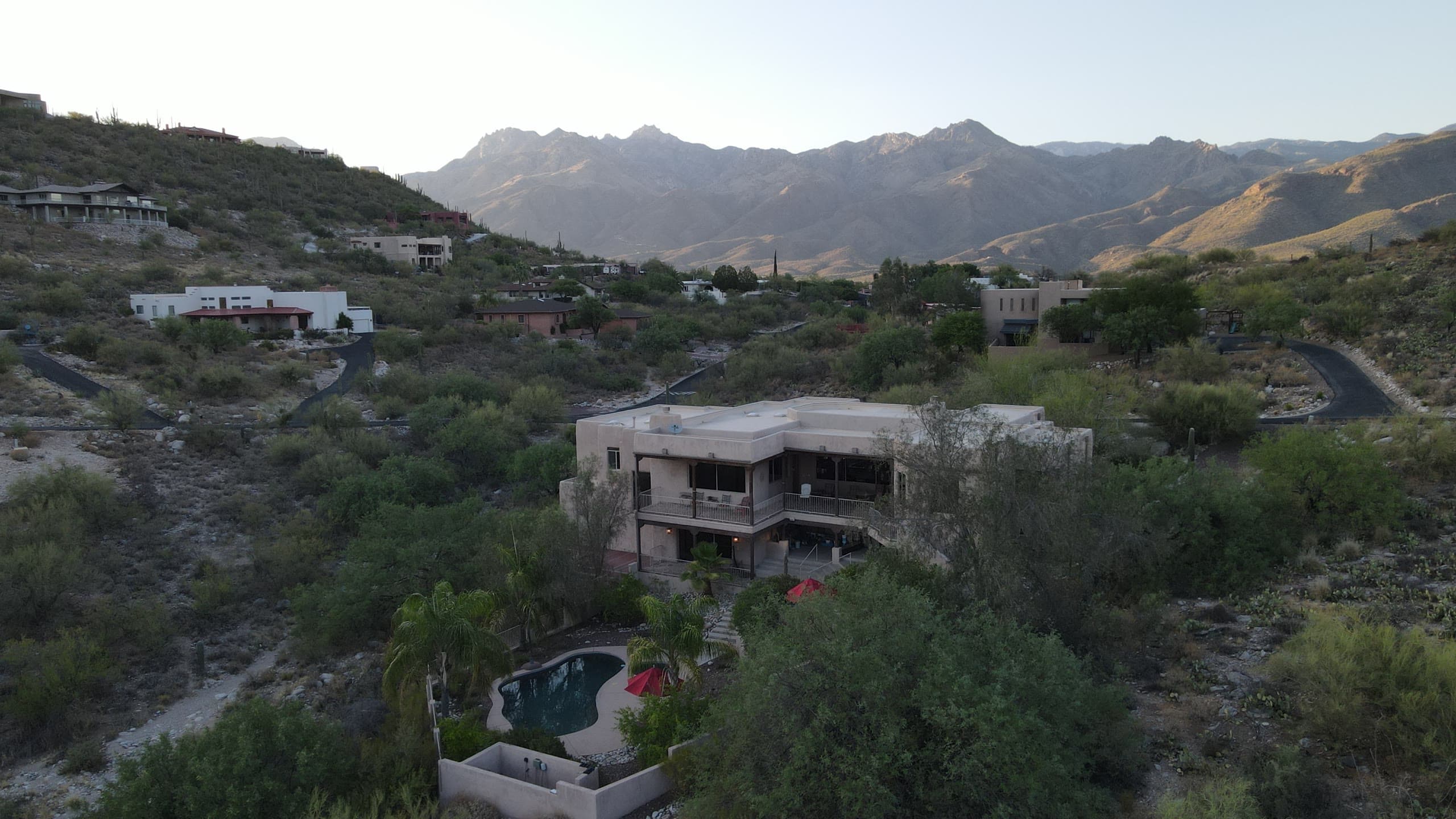 Hillside home with a pool at dusk, mountains beyond