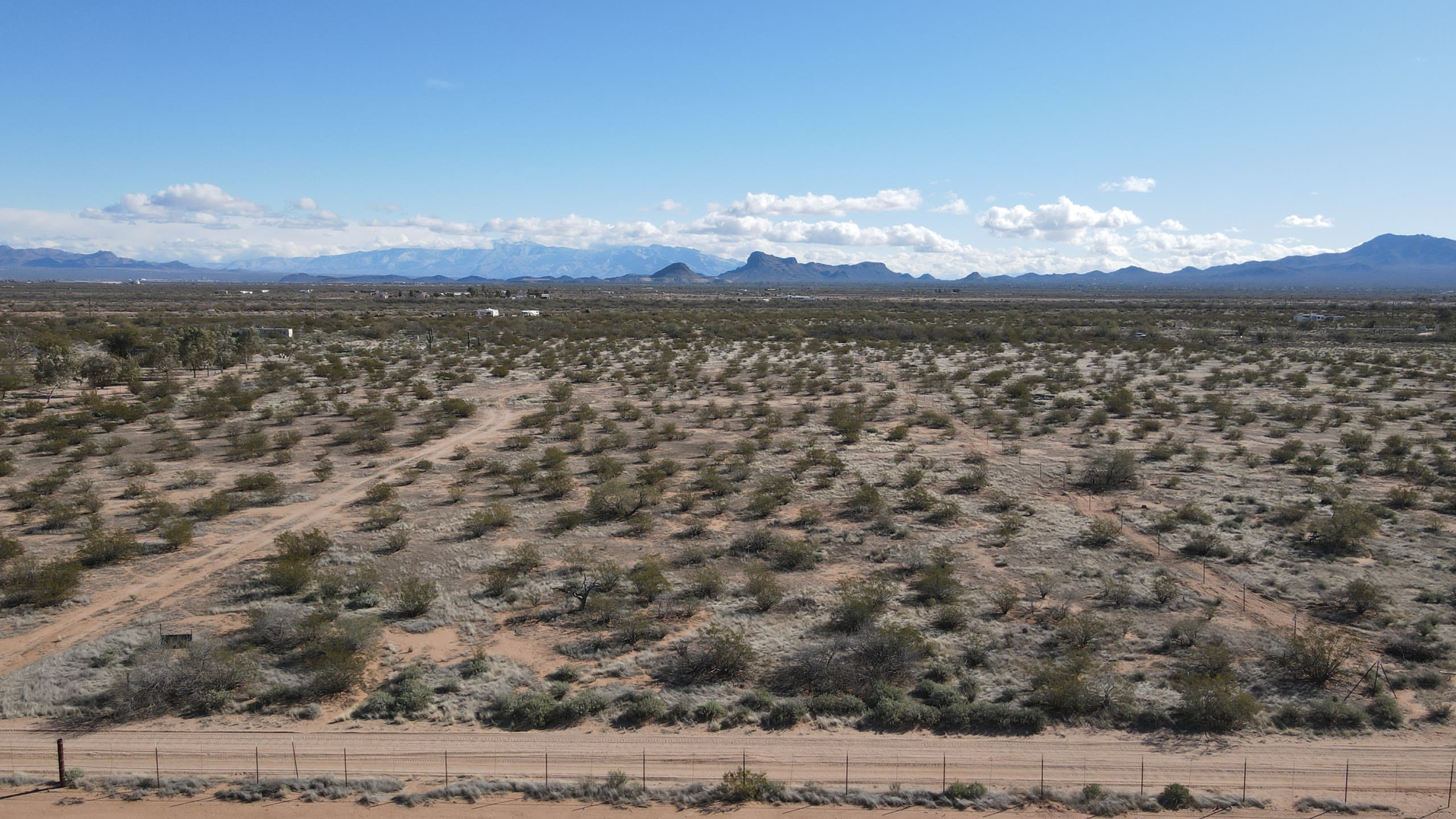 Open desert parcel behind a fence line under scattered clouds