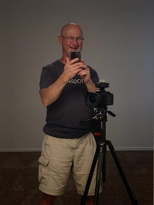Bill Hall standing beside a camera on a tripod